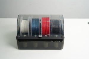 An image showing the Bambu Lab Automatic Material System showing 4 different colour filament spools: white, blue, red, and black